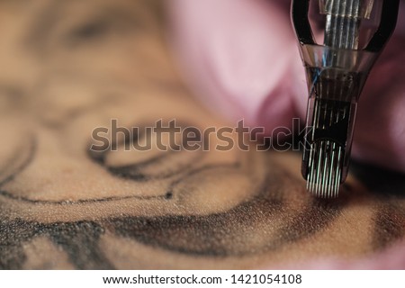 Close-up of a tattoo needle. The process of the tattoo master. Pink women's protective gloves. Tattoo sketch nun.
