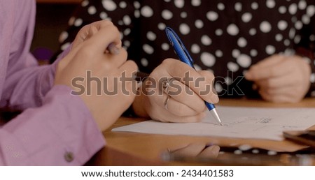 Close-up teacher explains task to student, draws with pen on paper. Drawing diagrams and illustrations on a piece of paper, ensuring the student grasps the material through visual aids. No face.