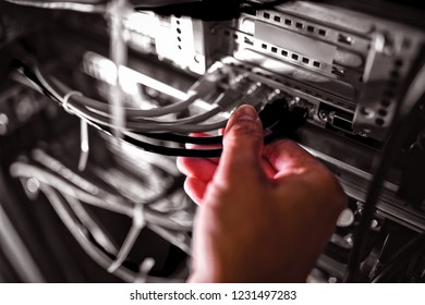 Close-Up of technician plugging patch cable in a rack mounted server in server room