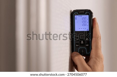 Close-up of a technician using a laser rangefinder in an apartment.