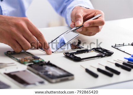 Close-up Of A Technician's Hand Fixing Damaged Screen On Mobile Phone