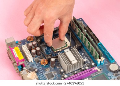 Close-up of a technician's hand installing a CPU processor into a motherboard socket on a minimalist pink background. Concept of computer assembly, hardware repair, IT maintenance, and technical DIY projects