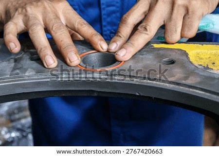 Close-up of a technician's hands carefully fitting a precision orange rubber O-ring gasket into a circular groove on a heavy-duty steel machine part.