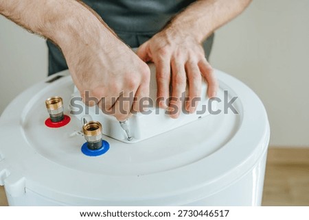 Close-up of a technician's hands using a screwdriver to repair an electric water heater