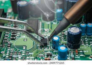 Close-up of a technician's hands in a workshop. The repairer is soldering an IC in a SOIC package to the circuit board of an electronic device. - Powered by Shutterstock