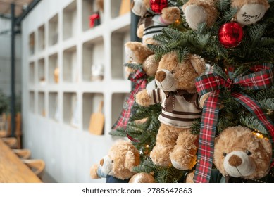 Close-up of teddy bears hanging on a Christmas tree with a red ribbon
