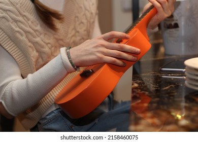 Closeup Of Teenage Girl Playing Orange Ukulele. Music. Teens Singing And Playing. Indoor