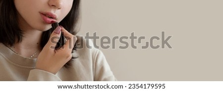Closeup Teenage girl putting makeup. Young woman looking at mirror and apply lipstick on lips in bedroom. Cosmetics for youth culture trend. Daily make-up. copy space