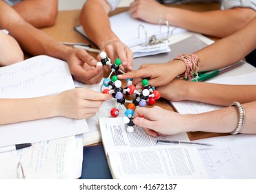 Close-up of teenagers studying and holding molecules in a library