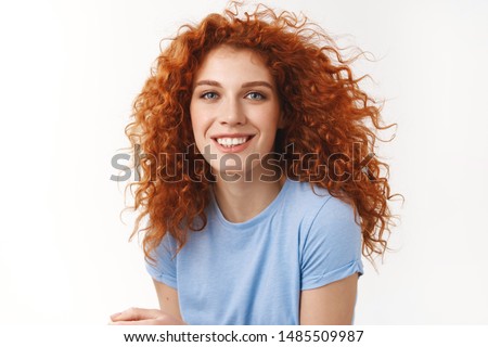Close-up tender alluring redhead woman with curly hair that floats in air, smiling joyfully and coquettish gaze camera, enjoy summer ocean breeze, strands floating in air, stand white background