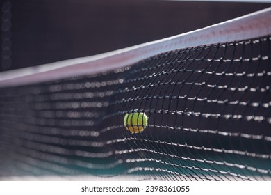 Close-up of tennis ball striking a net of tennis court outdoors, sunny weather - Powered by Shutterstock