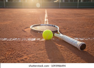 Close-up tennis racket and ball placed on court ground. 