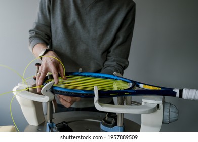 Close-up of tennis racket on electronic stringing machine. Process of replacement synthetic gut string before game. Hands of stringer.