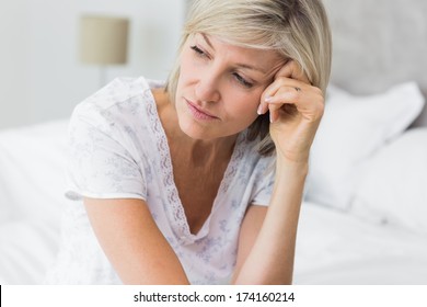 Closeup of a tensed mature woman sitting in bed at home - Powered by Shutterstock