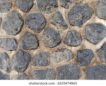 Close-up texture of black natural stone with cement joints.
