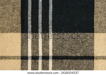 Close-up texture of brown and ivory checked tartan fabric. Traditional Scottish clothing. material for making shirts and skirts