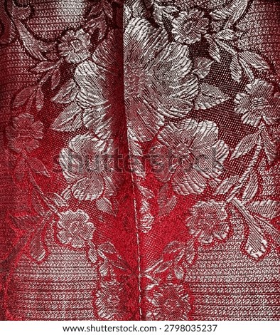 Close-up texture of elegant red and silver floral brocade fabric, luxurious jacquard textile background with woven flower pattern