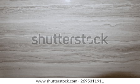 Close-up texture of light gray marble stone with natural wavy line patterns. The elegant and smooth marble surface is perfect for background, interior design, architecture, or modern decorative elemen