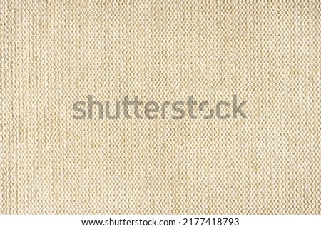 Close-up texture of natural beige coarse weave fabric or cloth. Fabric texture of natural cotton or linen textile material. Blue canvas background. Decorative fabric for upholstery, furniture, walls