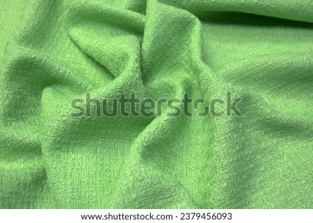 Close-up texture of natural green or salad color fabric or cloth in same color. Fabric texture of natural cotton, silk or wool, or linen textile material. Green canvas background.