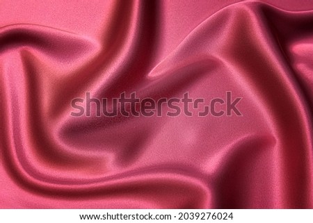 Close-up texture of natural red or pink fabric or cloth in same color. Fabric texture of natural cotton, silk or wool, or linen textile material. Red and orange canvas background.
