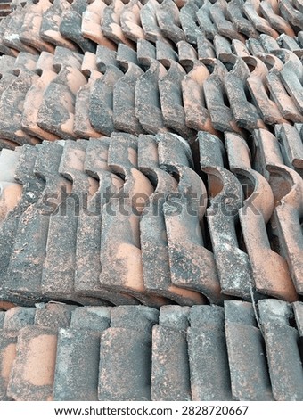 Close-up texture of old weathered clay roof tiles with dark stains, moss, dirt, and signs of aging. Traditional roofing material with a rustic and natural surface pattern.