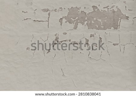 Close-up texture of an old, weathered plaster wall with significant cracking, crazing, and areas where the top layer of paint is peeling away, Estonia, Europe.