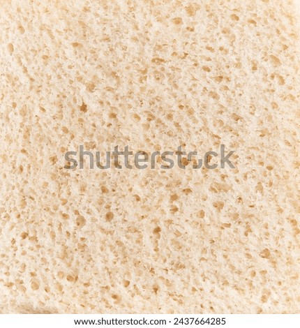 Close-up texture of a piece of white bread, emphasizing its porous surface and airy crumb for culinary contexts.