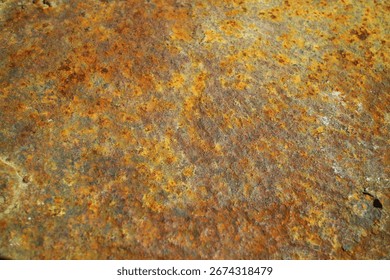 Close-up texture of rusty metal surface with corrosion and weathered patterns in orange, brown, and yellow tones
