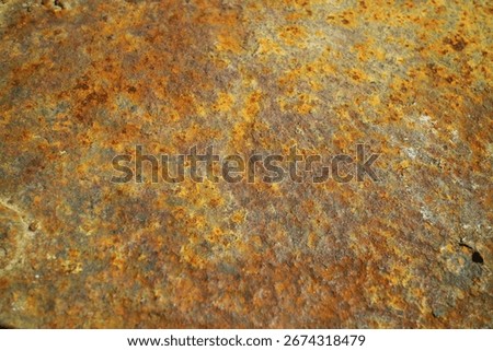 Close-up texture of rusty metal surface with corrosion and weathered patterns in orange, brown, and yellow tones
