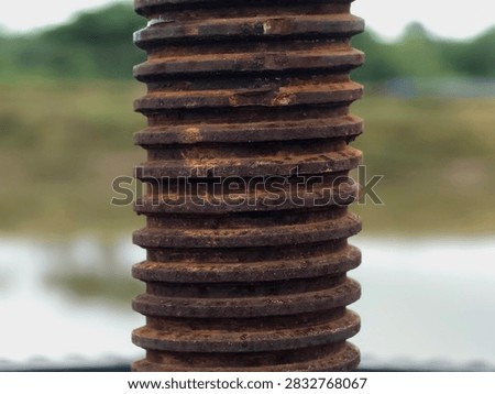 Close-up texture of a rusty threaded metal rod or large screw.
