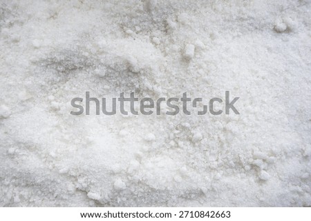 A close-up texture shot of white table salt crystals forming a granular mound, highlighting the crystalline shapes and fine detail of each grain.