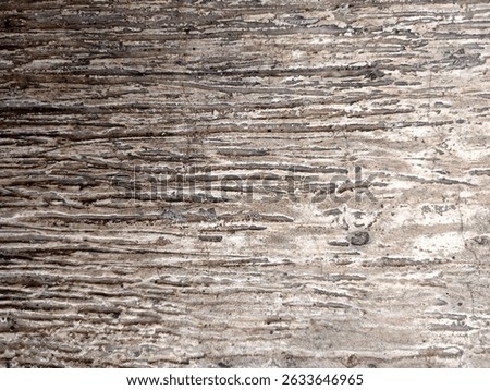 Close-up texture of a weathered and aged stone surface with natural horizontal striations and earthy tones. Ideal for use as a background or texture in design projects, offering a rustic and aesthetic