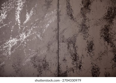 Close-up of a textured backdrop split into two sections. The left side is metallic silver, and right side is dark gray, both featuring similar mottled patterns and a rough surface. Copy ad text space