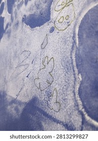 Close-up of a textured blue surface featuring naive, hand-drawn sketches and watercolor effects, evoking a sense of creativity and simplicity.