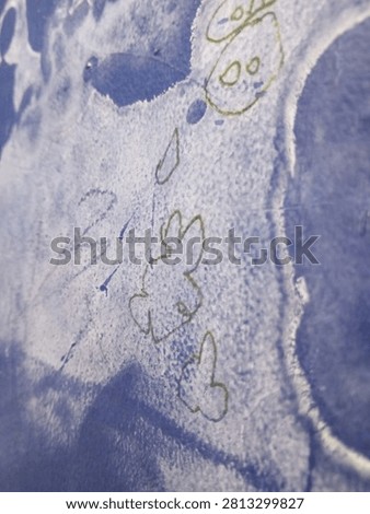 Close-up of a textured blue surface featuring naive, hand-drawn sketches and watercolor effects, evoking a sense of creativity and simplicity.