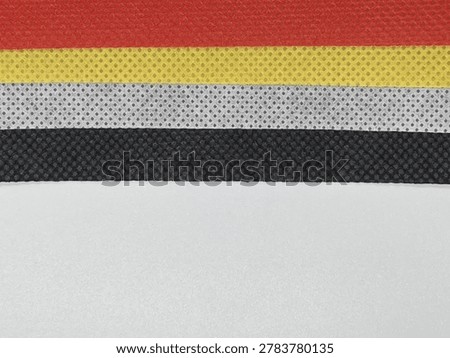 Close-up of a textured surface featuring horizontal stripes in red, yellow, white, black, and gray.
