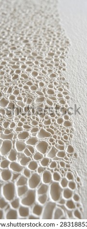 Close-up of a textured surface with a pattern of irregular, concave shapes, resembling a honeycomb or cells