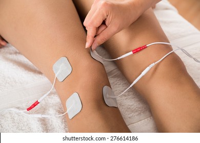 Close-up Of Therapist Placing Electrodes On Woman's Knee