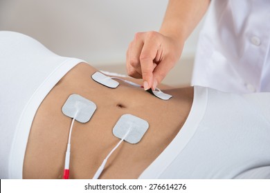 Close-up Of Therapist Placing Electrodes On Woman's Stomach