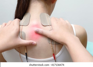 Closeup of therapist placing electrodes on woman's back
