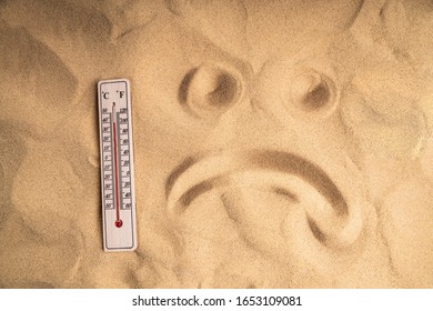 Close-up Of Thermometer With High Temperature On Sand And Sad Face