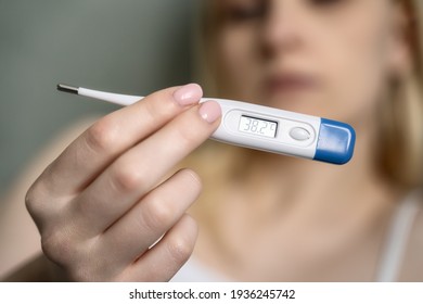 Close-up thermometer. Mother measuring temperature of her ill kid. Sick child with high fever laying in bed and mother holding thermometer. Hand on forehead. - Shutterstock ID 1936245742