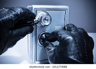 Close-up Of A Thief's Hand Using Stethoscope While Unlocking Safe