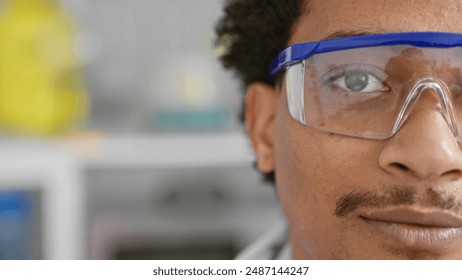 Close-up of a thoughtful man with safety glasses in a laboratory setting.