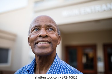 Close-up of thoughtful senior man smiling while looking up at nursing home - Powered by Shutterstock