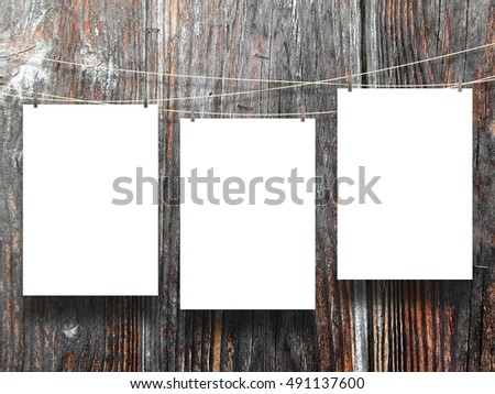 Close-up of three blank frames hanged by pegs against dark brown wooden boards background