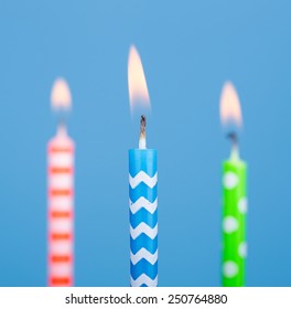 Closeup of three burning birthday candles on a blue background
