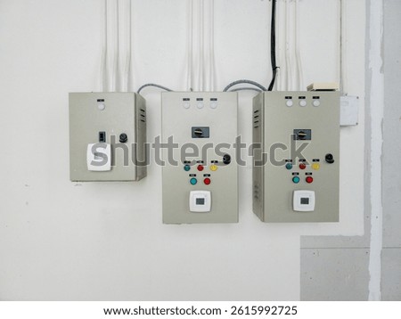 Close-up of three electrical control panels on white wall with conduit pipes and switches, suitable for engineering, industrial system, facility maintenance or electrical power installation use.