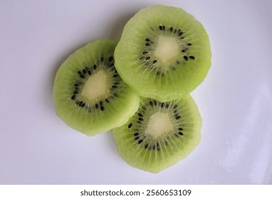 Close-up of three fresh kiwi slices on a white background, highlighting their vibrant green color, black seeds, and juicy texture. Perfect for food, health, or nutrition-related concepts and vitality. - Powered by Shutterstock